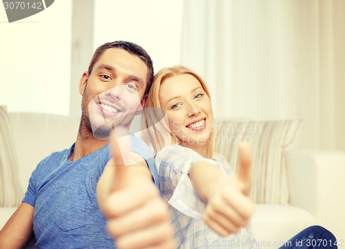 Image of smiling happy couple at home showing thumbs up