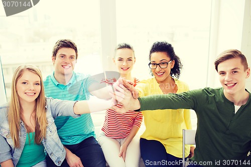 Image of smiling students making high five gesture sitting