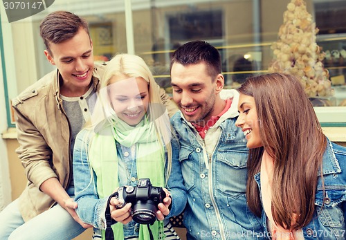 Image of group of smiling friends with digital photocamera