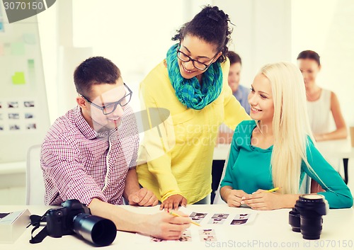 Image of smiling team with printed photos working in office