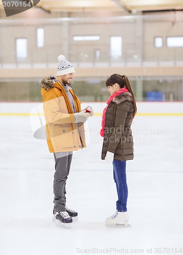 Image of happy couple with engagement ring on skating rink