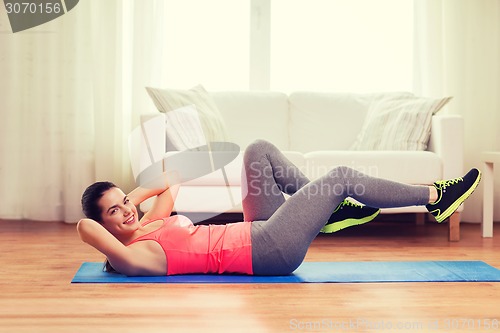 Image of smiling girl doing exercise on floor at home
