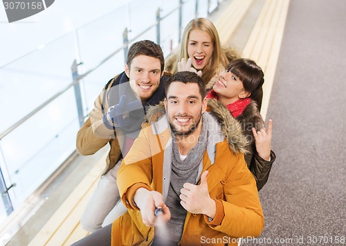 Image of happy friends taking selfie on skating rink