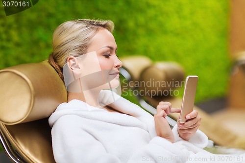 Image of beautiful young woman with smartphone at spa