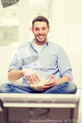 Image of smiling man watching sports at home