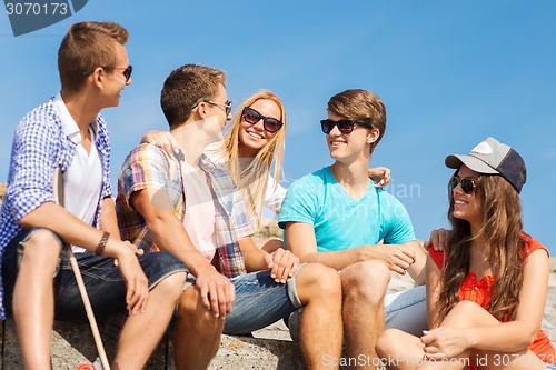 Image of group of smiling friends sitting on city street