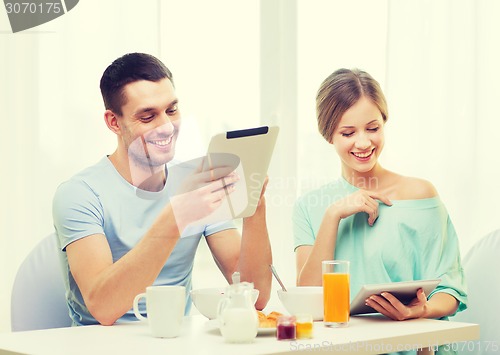 Image of smiling couple with tablet pc reading news