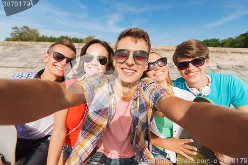 Image of group of smiling friends making selfie outdoors