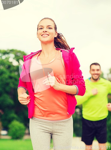 Image of smiling couple running outdoors