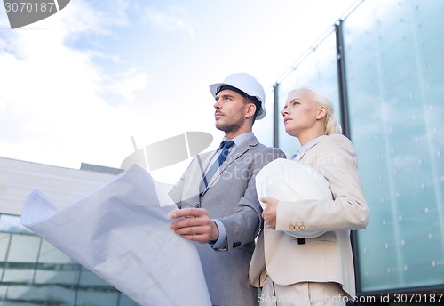 Image of businessmen with blueprint and helmets