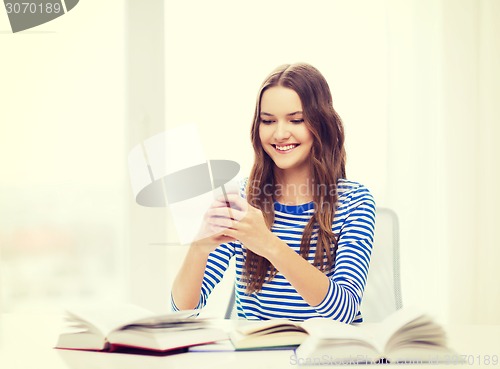 Image of smiling student girl with smartphone and books