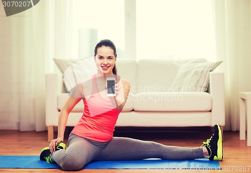 Image of smiling teenage girl streching on floor at home