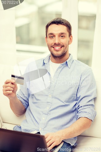 Image of smiling man working with laptop and credit card