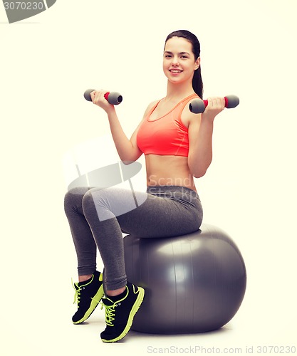 Image of teenager with dumbbells sitting on fitness ball