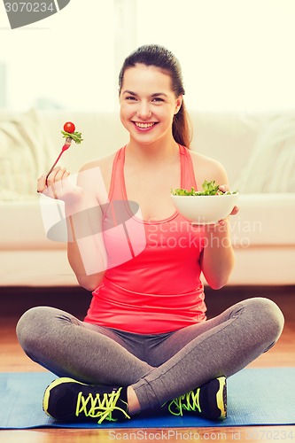 Image of smiling teenage girl with green salad at home