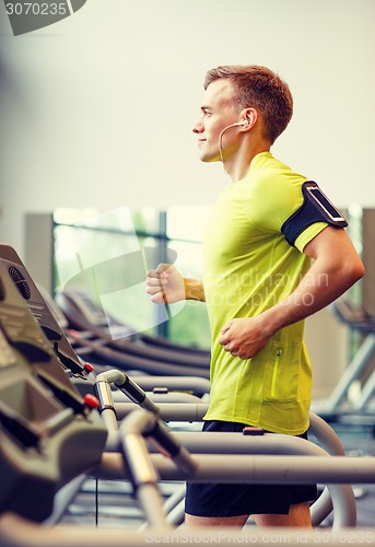 Image of smiling man exercising on treadmill in gym