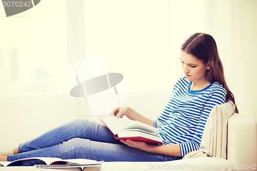 Image of calm teenage girl reading book on couch