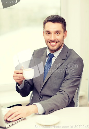 Image of smiling businessman with laptop and coffee