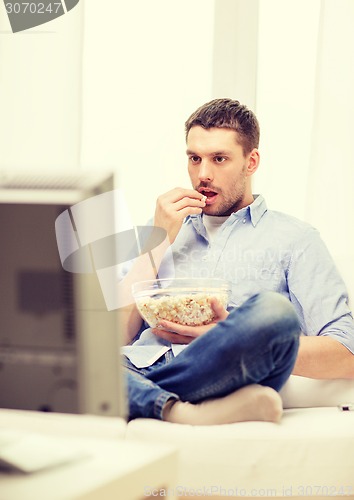 Image of smiling man watching sports at home