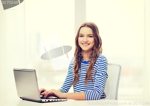 Image of smiling teenage gitl with laptop computer at home