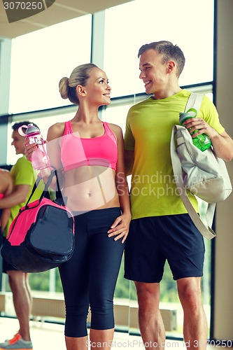 Image of smiling couple with water bottles in gym