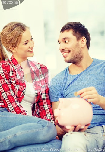 Image of smiling couple with piggybank sitting on sofa