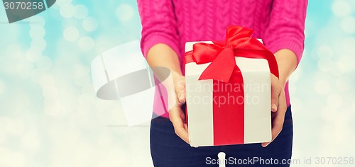 Image of close up of woman in pink sweater holding gift box