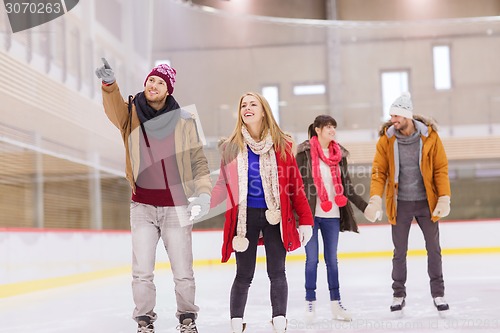 Image of happy friends pointing finger on skating rink