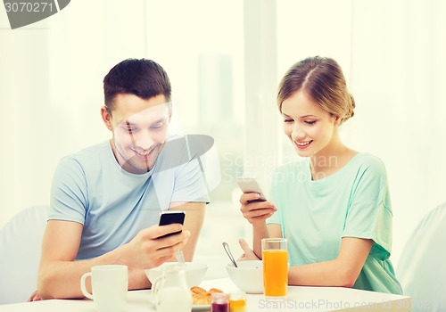 Image of smiling couple with smartphones reading news