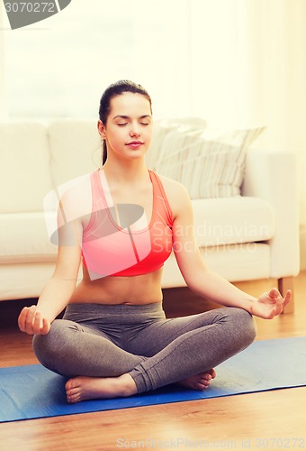 Image of smiling teenager meditating at home