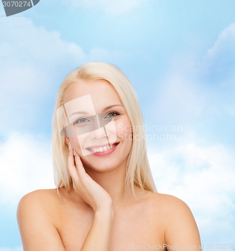 Image of smiling young woman touching her face skin