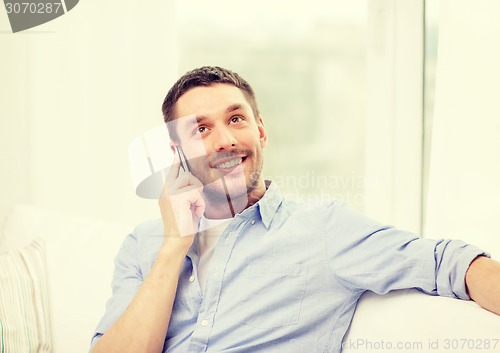 Image of smiling man with smartphone at home