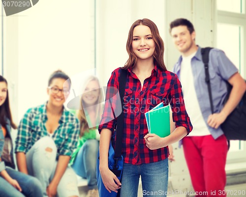 Image of smiling female student with bag and notebooks