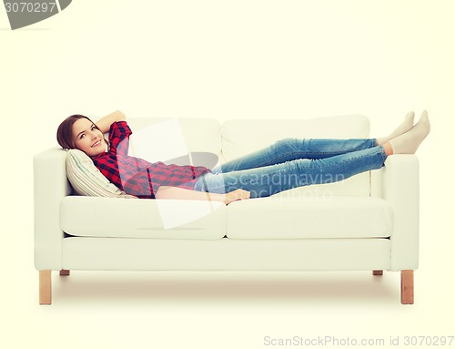 Image of smiling teenage girl lying on sofa