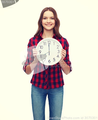 Image of young woman in casual clothes with wall clock