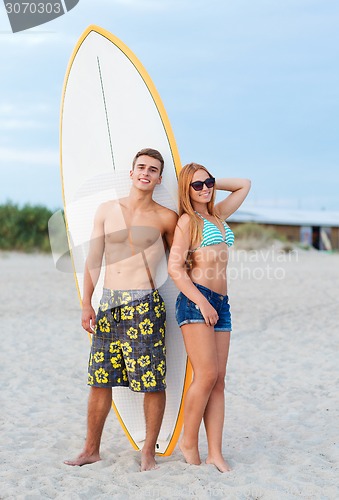 Image of smiling couple in sunglasses with surfs on beach