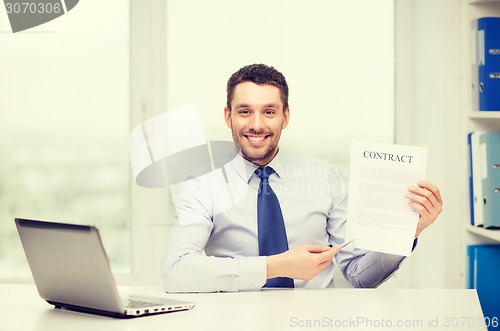 Image of businessman with laptop and contract at office