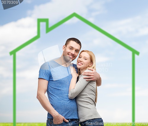 Image of smiling couple hugging over green house