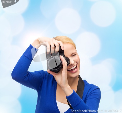 Image of smiling woman taking picture with digital camera