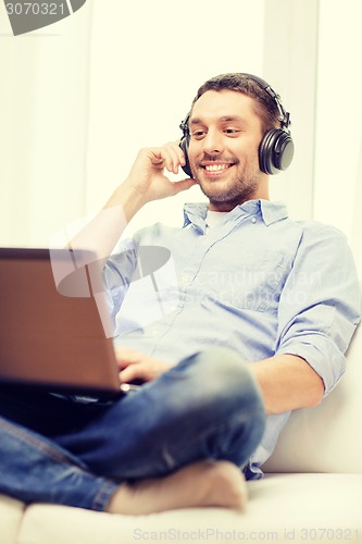 Image of smiling man with laptop and headphones at home