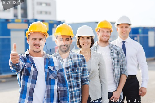 Image of group of smiling builders in hardhats outdoors