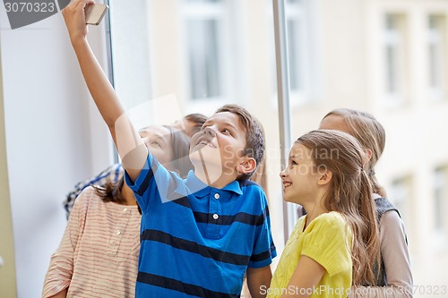 Image of group of school kids taking selfie with smartphone