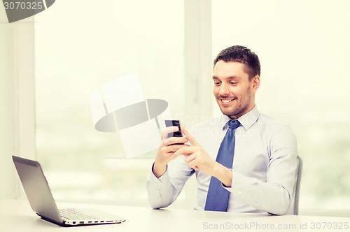 Image of businessman with laptop and smartphone at office