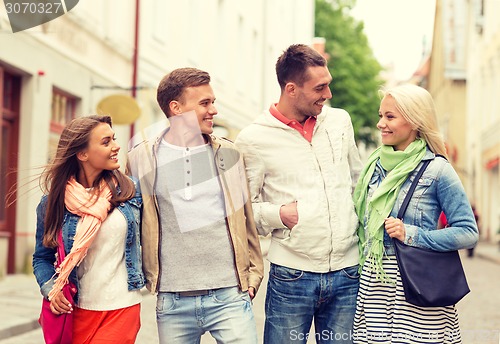 Image of group of smiling friends walking in the city