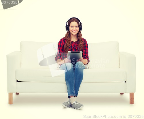 Image of girl sitting on sofa with headphones and tablet pc