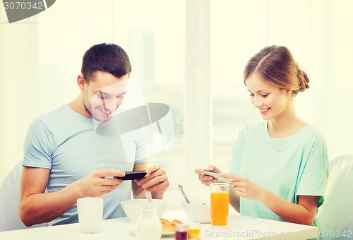 Image of smiling couple with smartphones taking picture