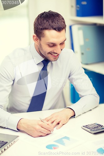 Image of smiling businessman with laptop and documents