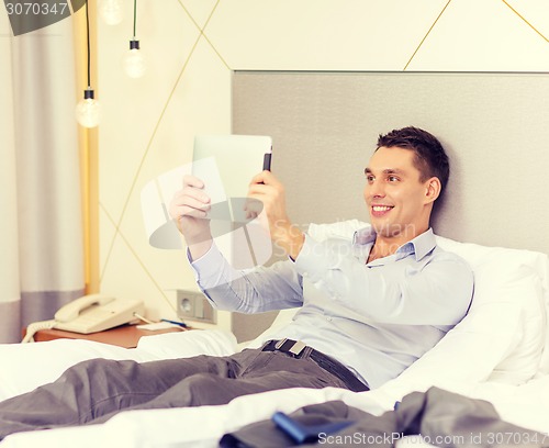 Image of happy businesswoman with tablet pc in hotel room