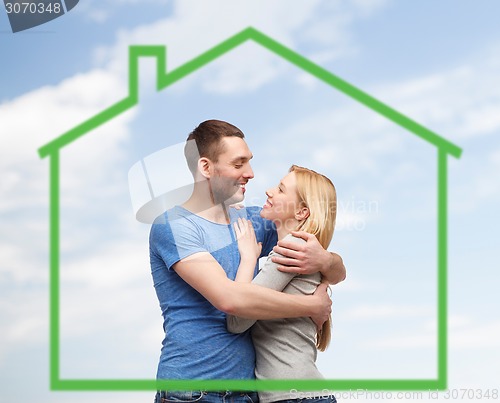 Image of smiling couple hugging over green house