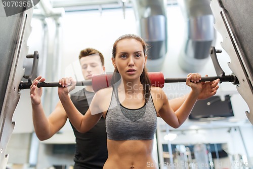 Image of man and woman with barbell flexing muscles in gym